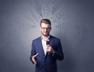 Businessman speaking into microphone with scribbles over his head 