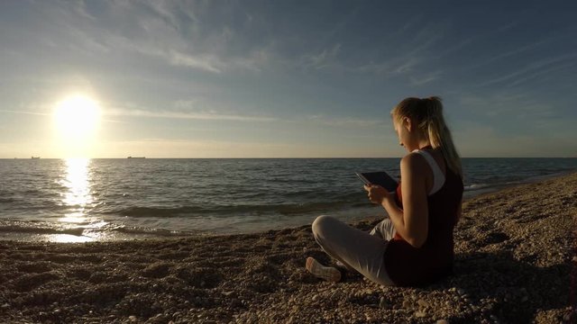 The girl on the beach takes a picture of the sunset on the beach.