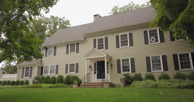 Slow dynamic drone pull back of large green house and trees
