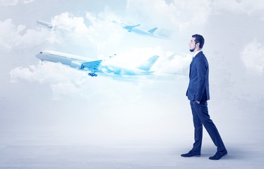 Obraz premium Elegant businessman going somewhere with briefcase and airplane on the background 