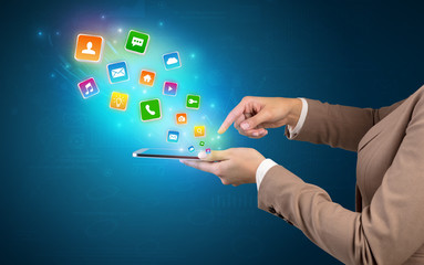 Hand holding tablet and application icons falling inwards
