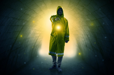 Fototapeta premium Ugly man in raincoat walking with glowing lantern in a dark tunnel