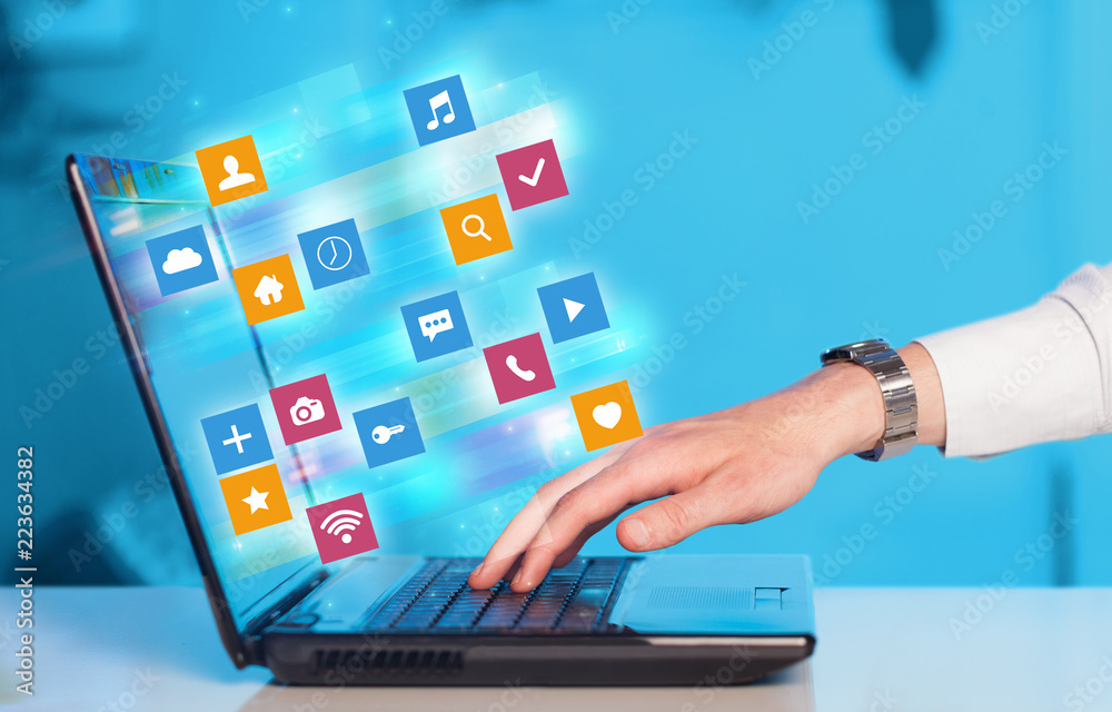 Poster Hand using laptop with colorful fast moving application icons and symbols concept
