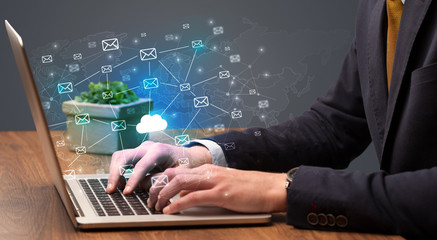 Businessman hand sending a bunch of messages on laptop with cloud computing concept
