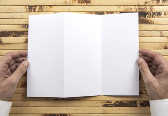 Mens hands holding white booklet