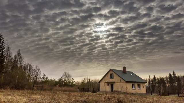 House under cloudy sky and sun at morning. 4k timelapse.