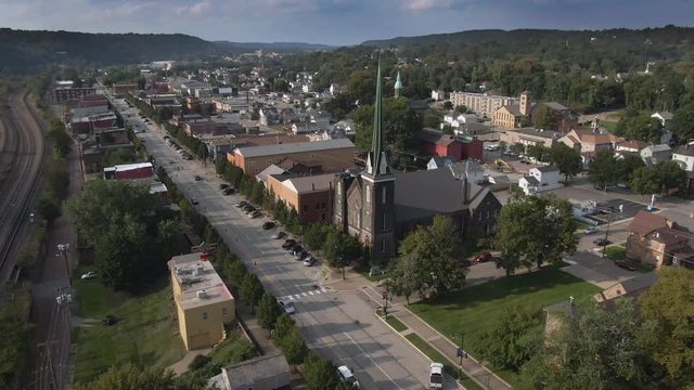 Forward aerial establishing shot of a small Pennsylvania town's business district on a late summer day. Pittsburgh suburbs.  	
