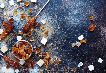 Sweet food background, assorted white and brown sugar on a dark background, top view
