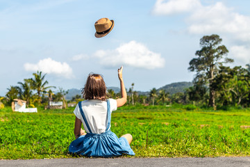 Tropical portrait of young happy woman with straw hat on a road with coconut palms and tropical...