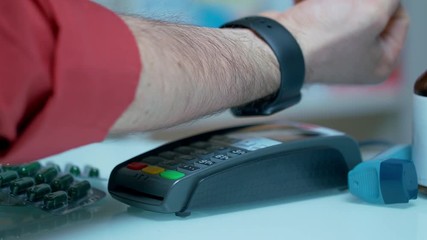 Customer using mobile payment with apple watch at drugstore. Close up of male hand paying for drugs with nfc technology. Contactless payment with smartwatch