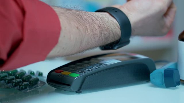 Customer using mobile payment with apple watch at drugstore. Close up of male hand paying for drugs with nfc technology. Contactless payment with smartwatch