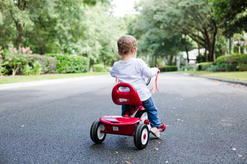 Young Child Toddler on Red Tricycle on a Neighborhood Street