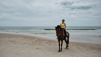 Young woman on beach with horse standing