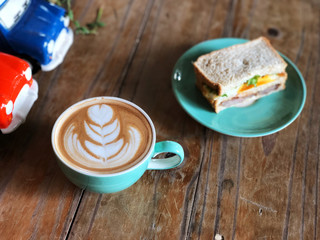 Fresh sandwich and Latte art coffee cup in green  plate set on the wooden table. Delicious Breakfast , Natural Light and copy space