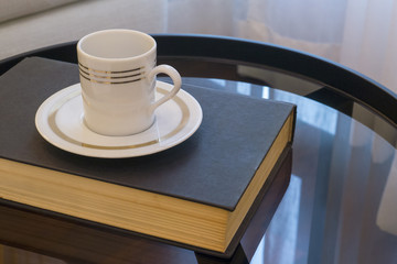 Cup of coffee on book cover isolated from black background.