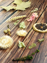 High angle view of dry wheat ears, fruit, green leaves, and plant materials on wooden background. Flat lay. Natural subject. Fresh and relaxed atmosphere. Dry plants can be used as decorations.