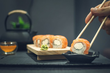 Philadelphia roll on wooden plate and fruit tea