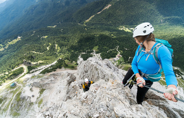 two young attractive mountain climbers on very exposed Via Ferrata in Alta Badia in the Italian...