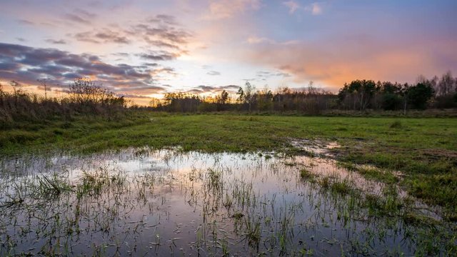 After sunset time-lapse with meadow and puddle under beautiful sky. 4k time-lapse, 3840x2160, 30fps.