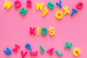 Early childhood development concept. Word kids written by plastic letters of toy alphabet on pink background top view copy space