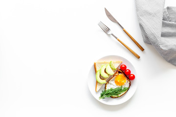 Healthy hearty breakfast. Fried eggs with vegetables near toast with avocado on white background top view copy space