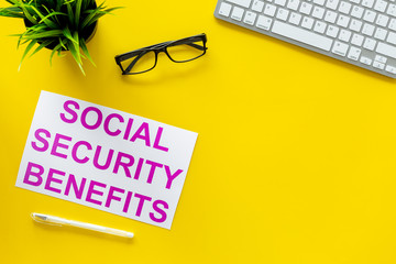 Printed words social security benefits on yellow office desk background with computer keyboard top view copy space