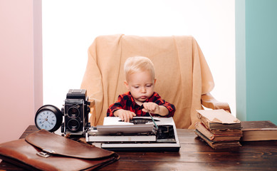 Fototapeta na wymiar Little boy secretary type paper on old typewriter at desk. Child learn typing on retro typewriter in office