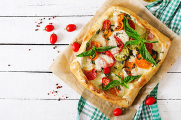 Mozzarella, tomatoes, basil savory pie on a white wooden background. Delicious food, appetizer in a...