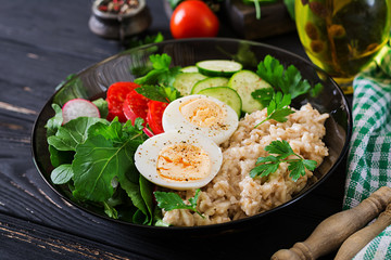 Healthy salad of fresh vegetables - tomatoes, cucumber, radish, egg, arugula and oatmeal on bowl. Diet food.