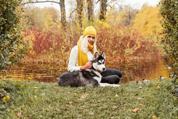 Naklejka na ściany i meble Cheerful woman and dog husky outdoor in the autumn park