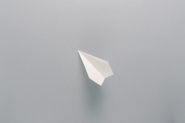 One flying paper plane over the grey background. Back to school and education concept. Plane as symbol of travelling and tourism.