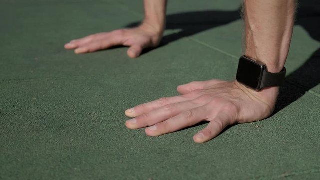 Close up of a caucasian man wearing smartwatches and doing push-ups.