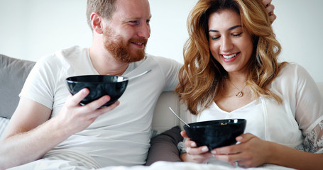 Young attractive couple having breakfast in bed