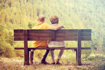 couple sitting outdoors in autumn, man holding his wife (romantic love concept)

