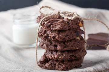 Chocolate chip chocolate cookies with chocolate pieces and milk on a vintage background. Moody vintage look.