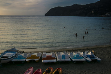 sunset beach view with empty boats in front of the sea. Levanto, Italy.