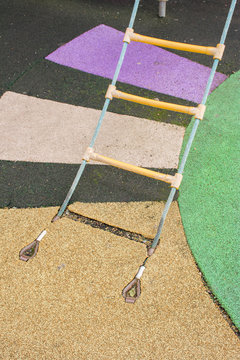 Fastening of a rope ladder to a rubber covering on a playground in the street