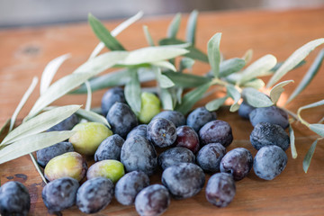 Dark olives with leaves on a wooden table