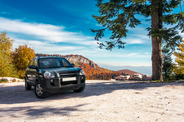 Fototapeta na wymiar SUV on the parking lot in mountains. beautiful mountainous scenery with huge rocky formation in the distance. wonderful deep autumn landscape. travel europe by car concept