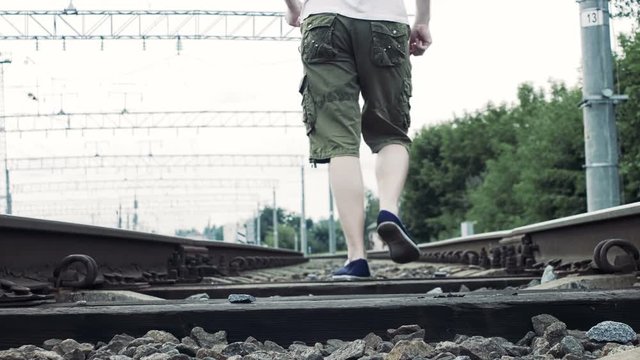 man with headphones walks along the railway, dangerous for life