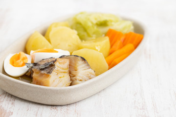 cod fish with boiled egg and vegetables on dish on white background