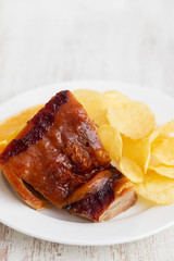 roasted piglet with potato chips and orange on white plate
