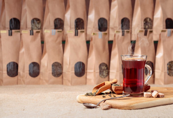 Glass of hot tea and wooden spoon with dried tea leaves.