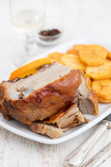 roasted piglet with potato chips and orange on white plate