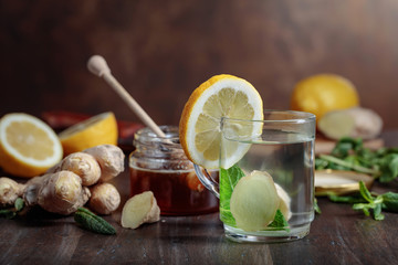 Ginger tea with honey , lemon and mint on old wooden table .
