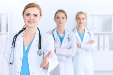 Fototapeta premium Group of medicine doctors offering helping hand for shaking hand or saving life. Partnership and trust concept in health care or medical cure 