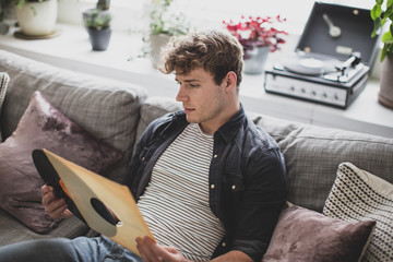 Young adult male looking at vinyl record