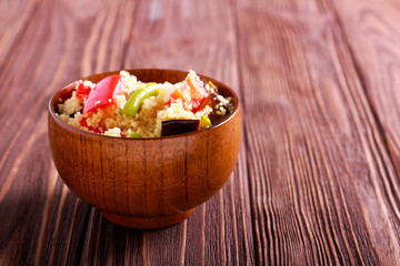 Couscous with vegetables in wooden bowl