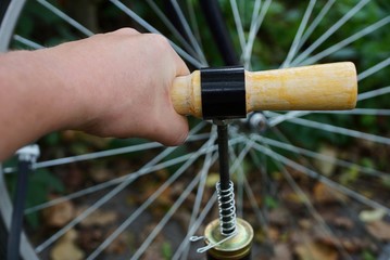 The hand with the pump pumps the wheel of a bicycle