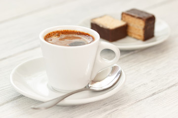 Cup of coffee with sweets on white wooden background in rustic style